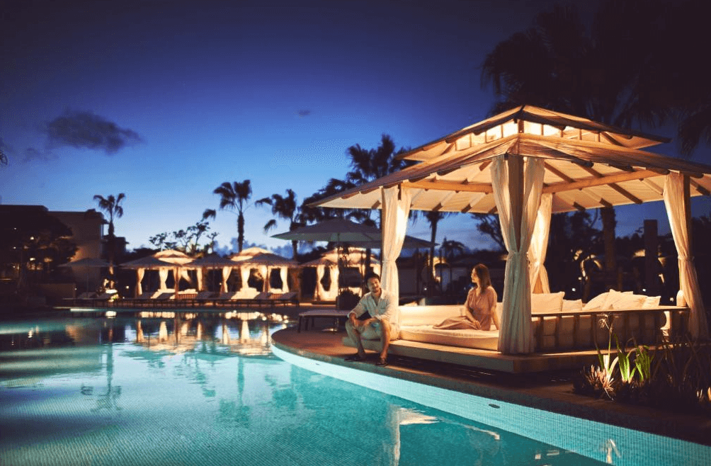 【石垣島住宿】石垣全日空洲際渡假村夜間泳池畔的涼亭空間，一對情侶悠閒坐在池邊，四周點燈浪漫，展現渡假村夜晚氛圍。