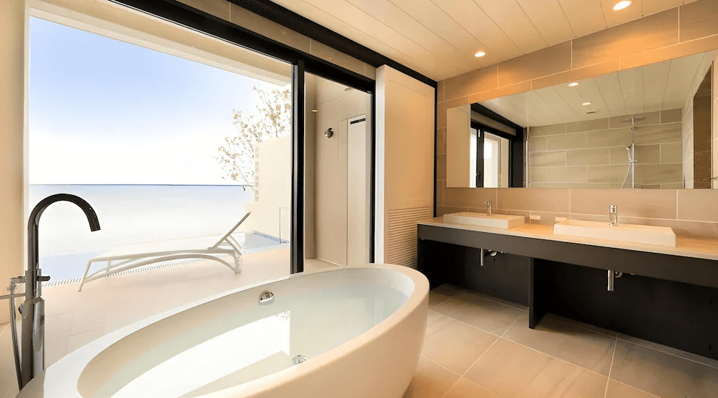 【石垣島住宿】VIVOVIVA豪華浴室設有獨立浴缸與雙洗手台，打開滑門即見專屬陽台與海景躺椅，營造奢華度假氛圍。