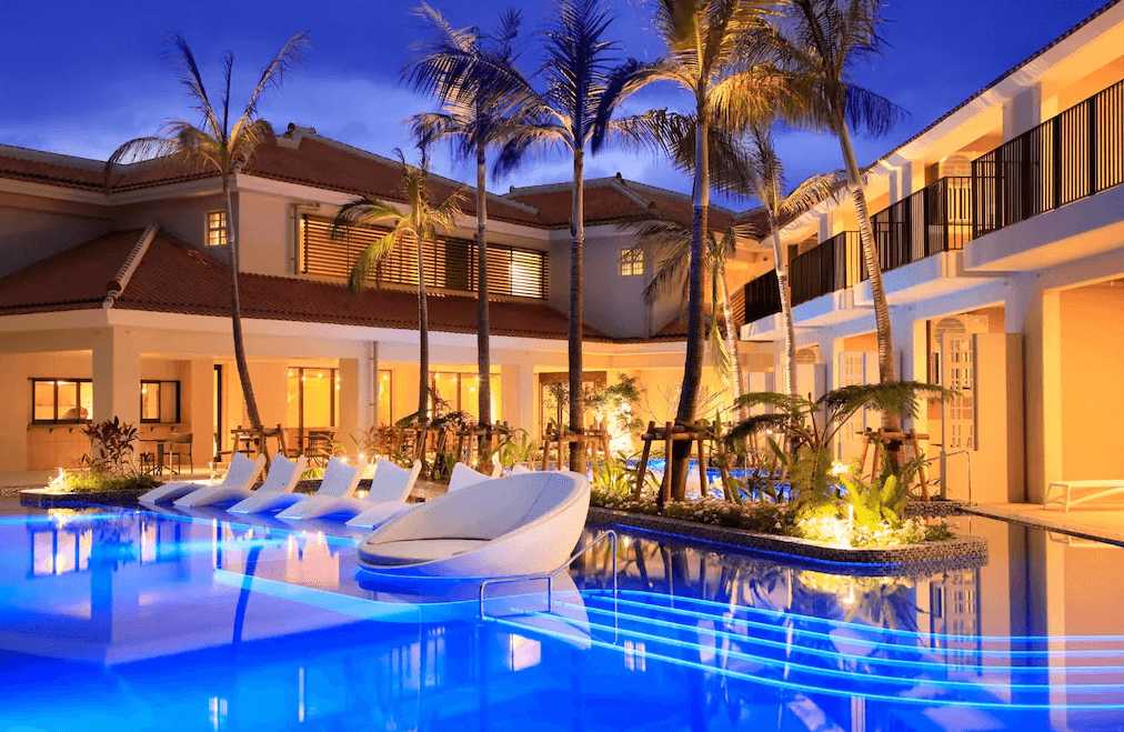 【石垣島住宿】"石垣島住宿精選示意圖"石垣島VIVOVIVA飯店夜色中的泳池庭園，熱帶椰子樹與躺椅環繞湛藍燈光泳池，展現夢幻海島風情。