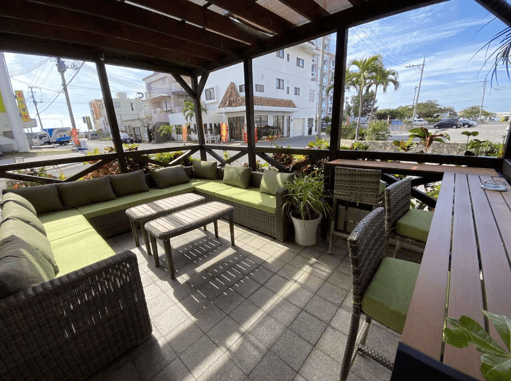 【石垣島住宿】石垣島帕提那酒店戶外休憩區，擁有舒適藤編沙發與高腳椅座位，綠色植栽點綴其間，適合享受城市微風與輕鬆交流。