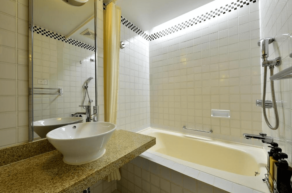 【石垣島住宿】石垣島艾克斯飯店浴室設有寬敞浴缸與獨立洗手台，白色瓷磚牆面搭配黑白邊飾，營造乾淨明亮的盥洗空間。