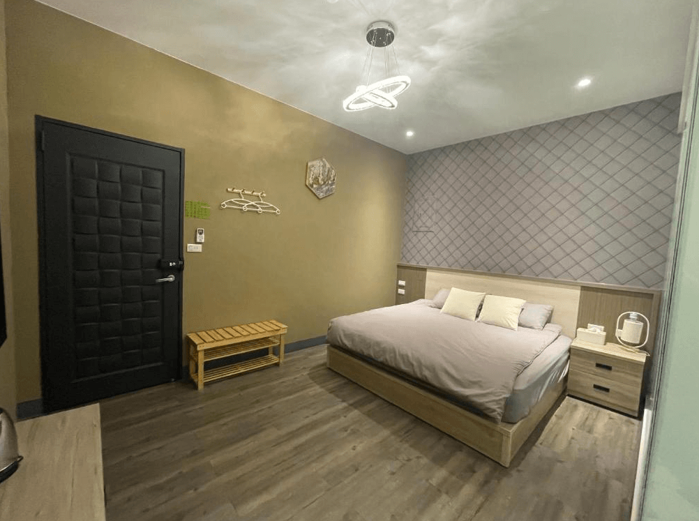 【竹山住宿】"竹山住宿精選示意圖"竹山。鄉間小路雙人房房型，牆面為沉穩灰褐色搭配菱格紋背景，設有一張加大雙人床與簡約木質家具，空間寬敞、氛圍寧靜。