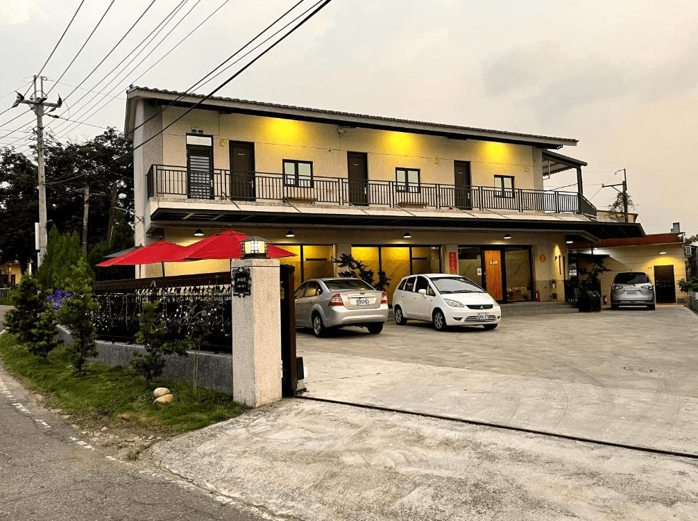 【竹山住宿】竹山。鄉間小路民宿外觀，全棟兩層樓建築設有寬敞停車場與庭院空間，黃光夜色點亮整棟建築，展現溫暖與安全感。