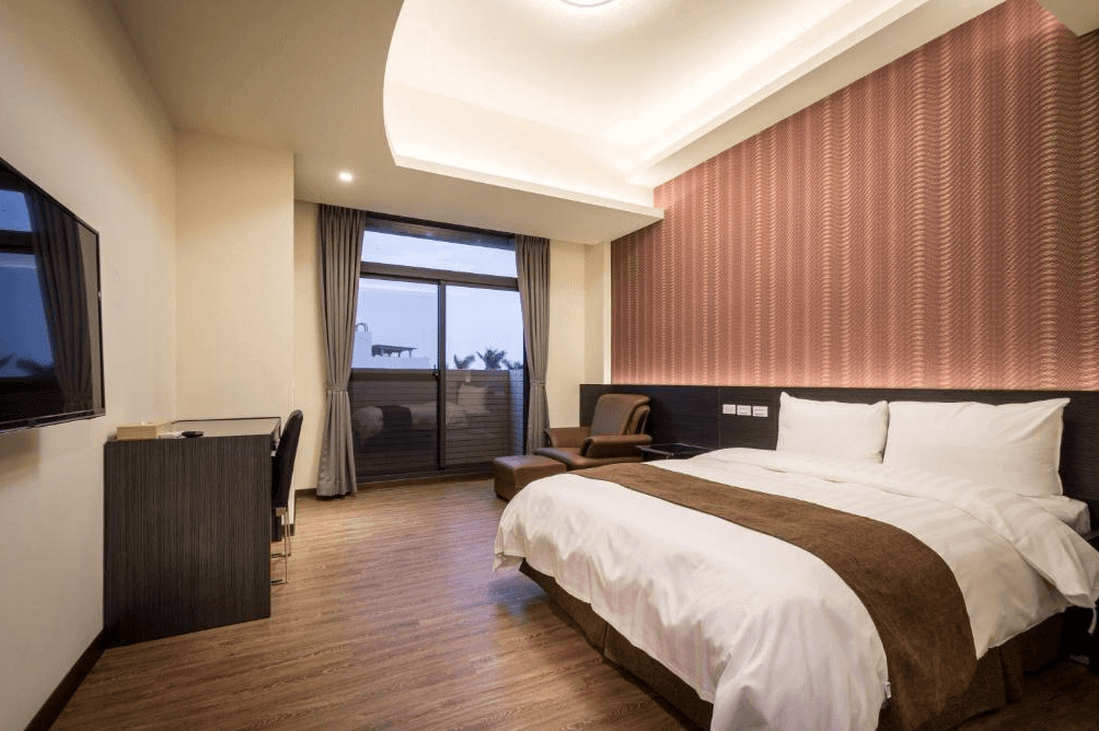 【西螺住宿】米都商務飯店的雙人房內部空間，配有大片窗景、現代簡約風格設計，大床、書桌與皮質休憩椅，環境明亮舒適。