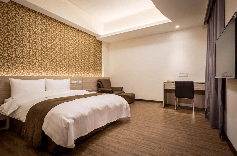 【西螺住宿】"西螺住宿精選示意圖"米都商務飯店另一款雙人房型，牆面裝飾有金色花紋圖樣，房內設有大床、皮質沙發與工作桌，空間寬敞整潔。