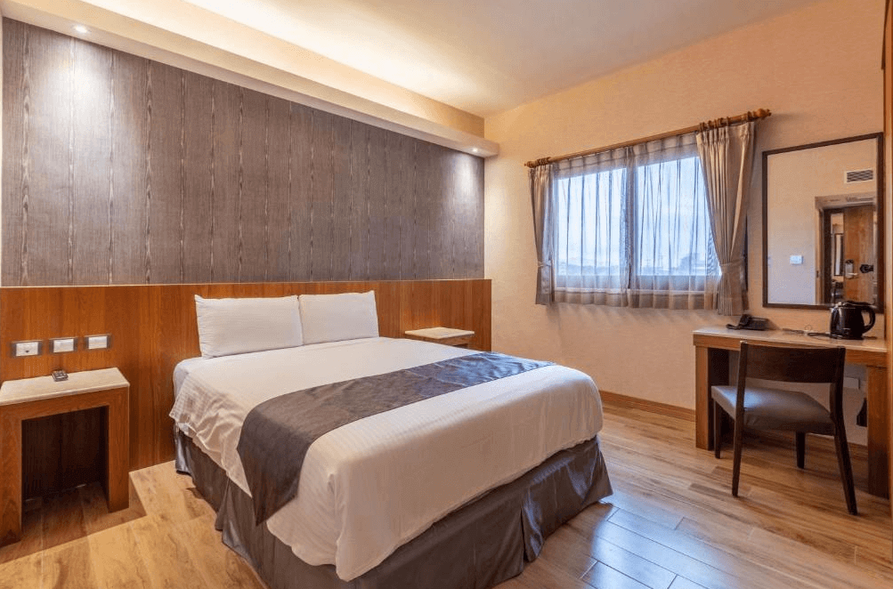 【花蓮寵物友善飯店】統茂渡假莊園標準雙人房，設有一張大床與木質書桌，窗外自然光灑入，空間簡潔雅緻，提供安靜放鬆的住宿環境。