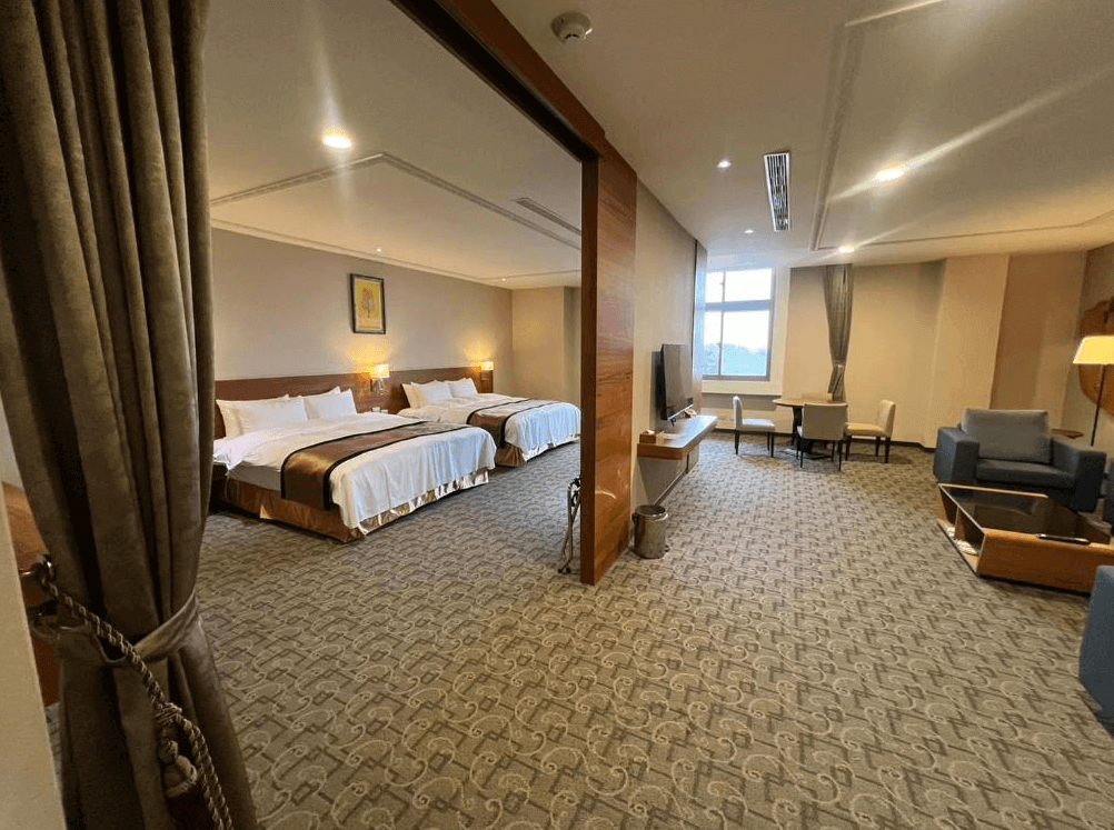 【古坑住宿】翠華會館的豪華家庭房，內部設有兩張雙人床，並分隔出客廳與餐桌空間，提供沙發休憩區與書桌，空間開闊，非常適合親子或多人同住。