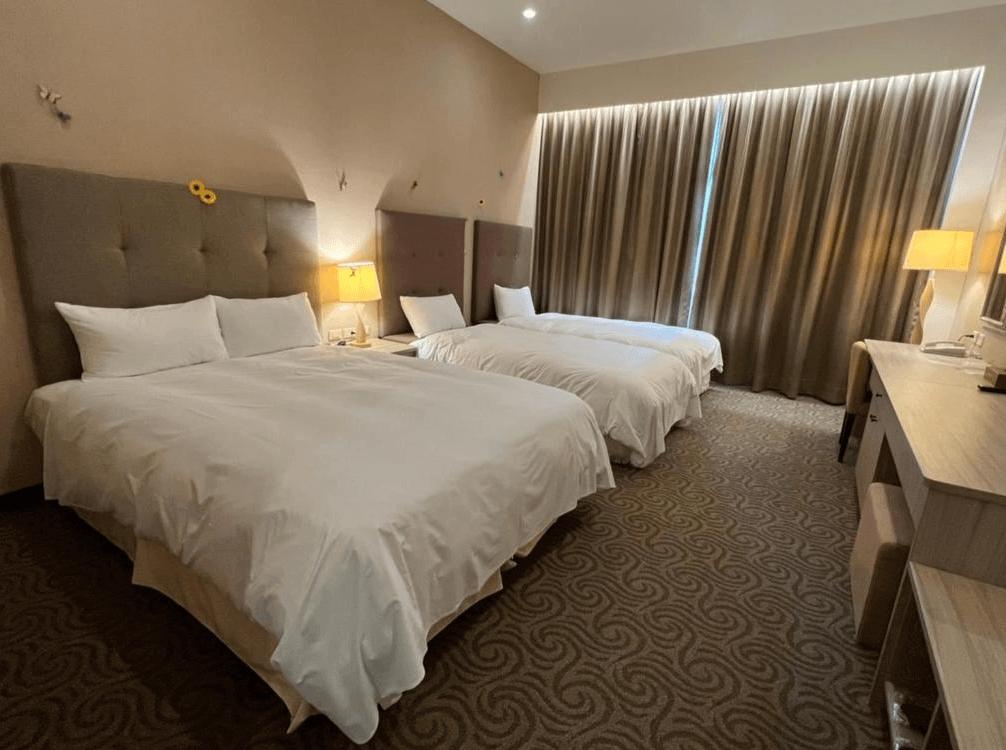 【古坑住宿】翠華會館的三人房設計，擁有兩張大床，搭配柔和燈光與簡約裝潢，地毯與窗簾設計一致，整體氛圍舒適，適合家庭或朋友同住。