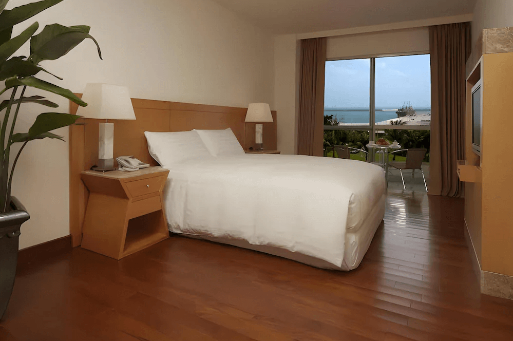 【花蓮寵物友善飯店】花蓮海悅酒店面海雙人房，搭配木質地板與簡潔設計，落地窗外可遠眺港口與藍天海岸，窗邊設有小桌椅，適合享用早餐或欣賞風景。