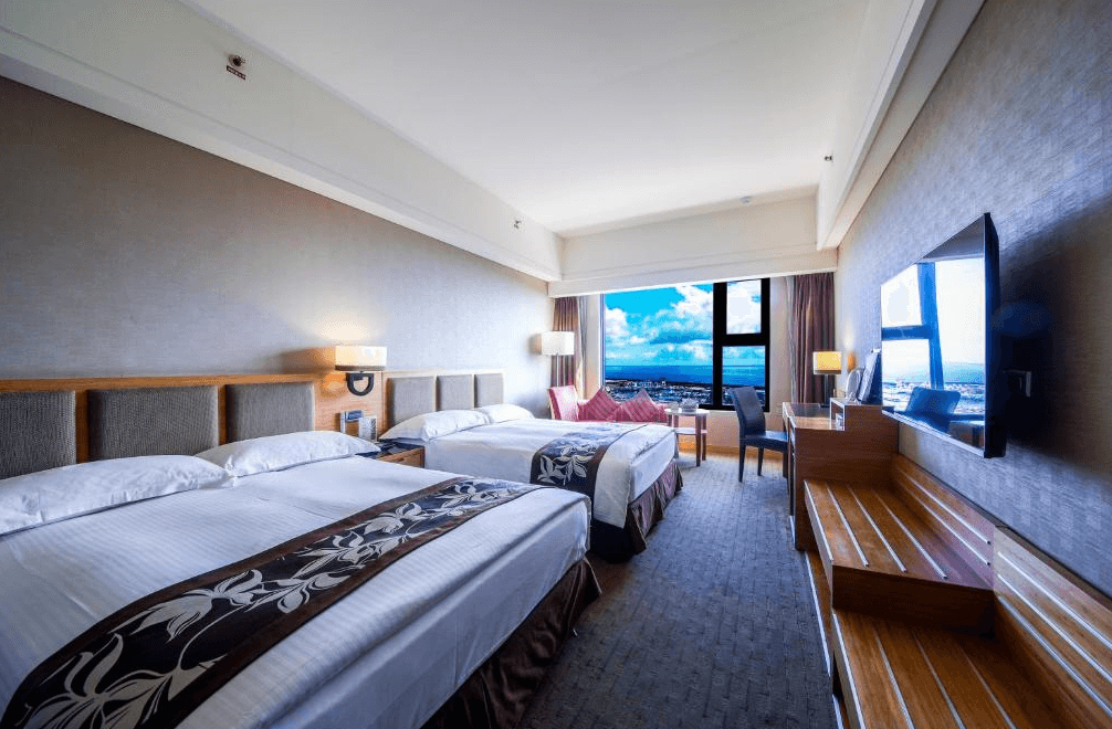 【花蓮寵物友善飯店】花蓮福容大飯店雙床海景房，房內設有兩張雙人床與沙發座位區，大片窗戶外可遠眺太平洋，室內布置典雅現代，是親子與家庭旅遊的理想選擇。