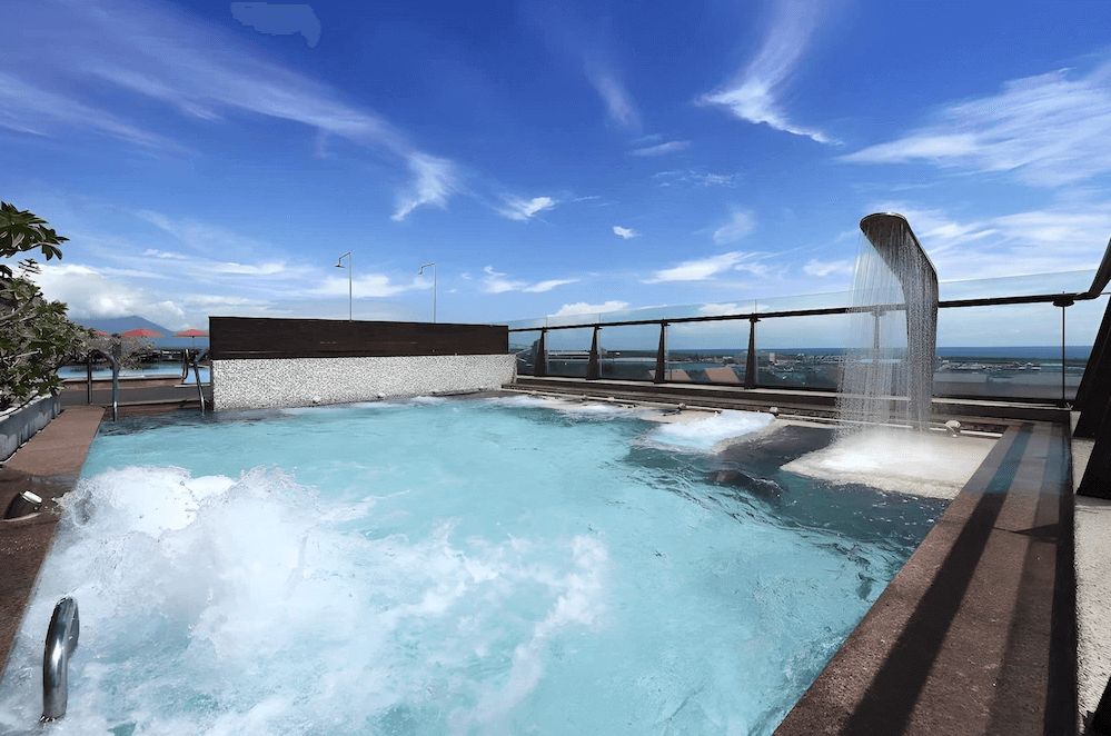 【花蓮寵物友善飯店】花蓮福容大飯店頂樓戶外SPA池，設有瀑布水柱與氣泡按摩池，遠眺太平洋與海港景緻，藍天白雲下享受放鬆的高空湯池體驗。