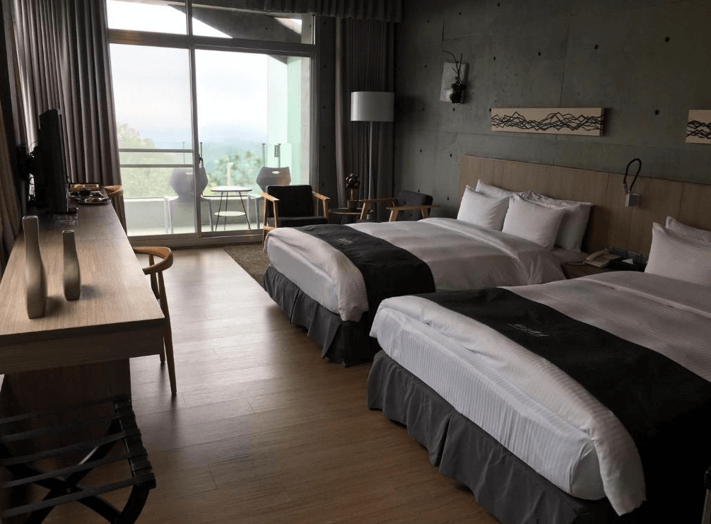 【古坑住宿】華山觀止-虫二行館的雙床房型，房間設計簡約俐落，採用自然木質地板與工業風水泥牆面，搭配大片玻璃窗與陽台，提供絕佳視野。