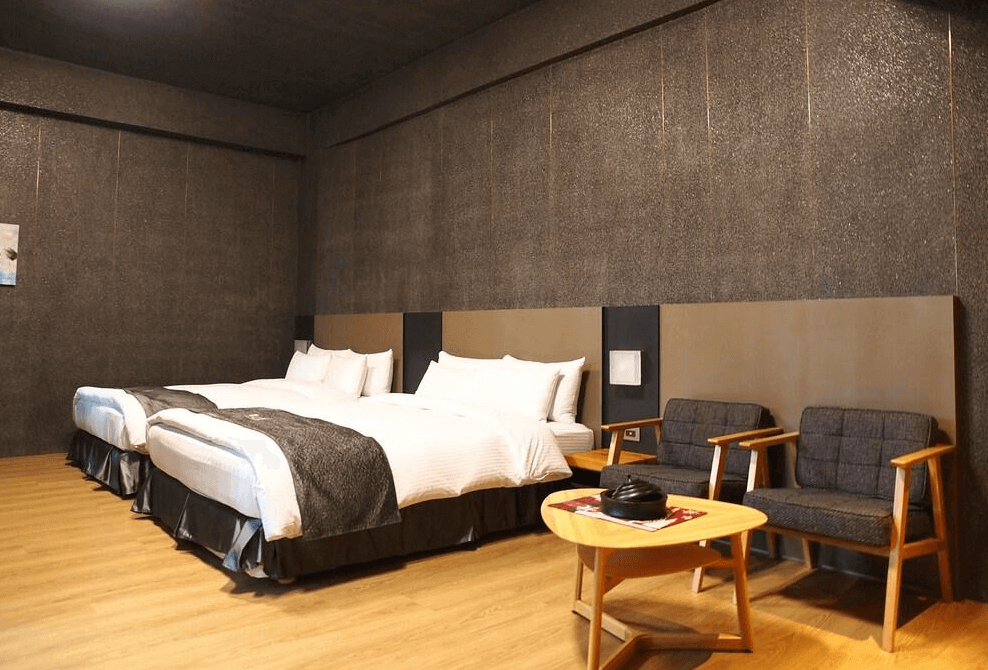 【古坑住宿】華山觀止-虫二行館的四人房，配有兩張大床與簡約的休憩空間，深色牆面與木質地板營造溫暖沉穩的氛圍，適合家庭或朋友入住。