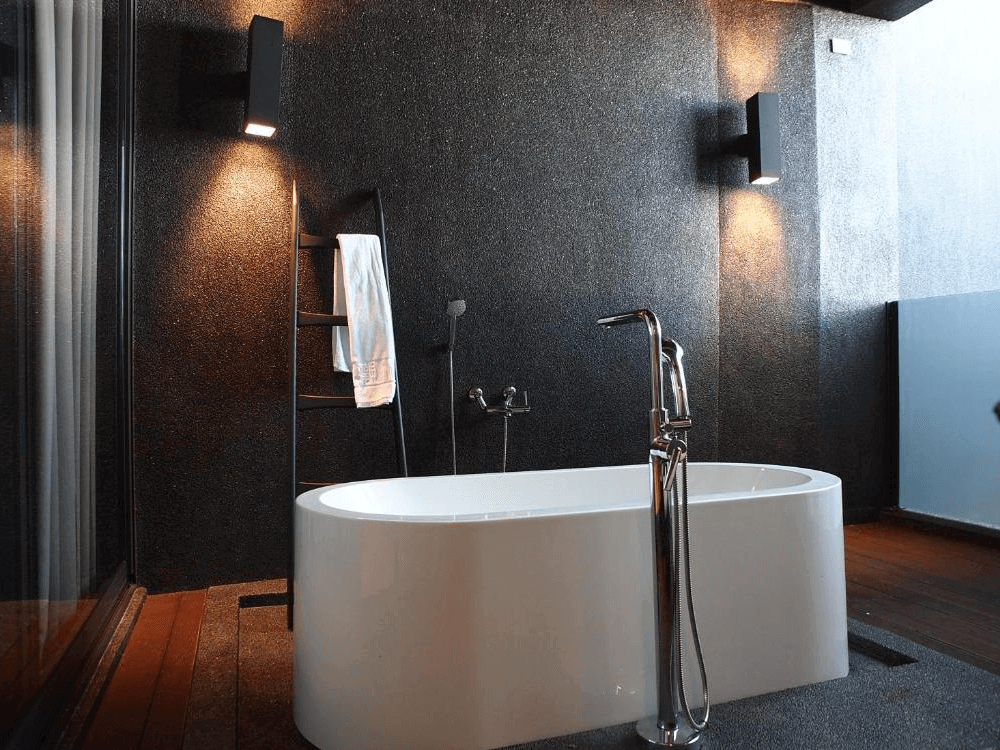 華山觀止-虫二行館的半露天浴缸設計，搭配黑色質感牆面與暖色燈光，設有獨立浴缸與現代感十足的淋浴設備，營造高雅私密的泡澡空間。