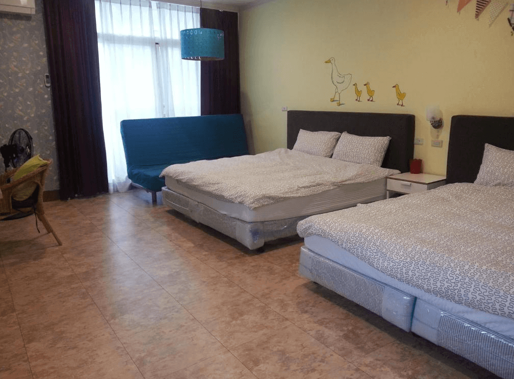 【西螺住宿】西螺後街童畫民宿家庭房，設有兩張雙人床與藍色沙發床，牆面上有可愛的鴨子親子插畫，空間寬敞明亮。