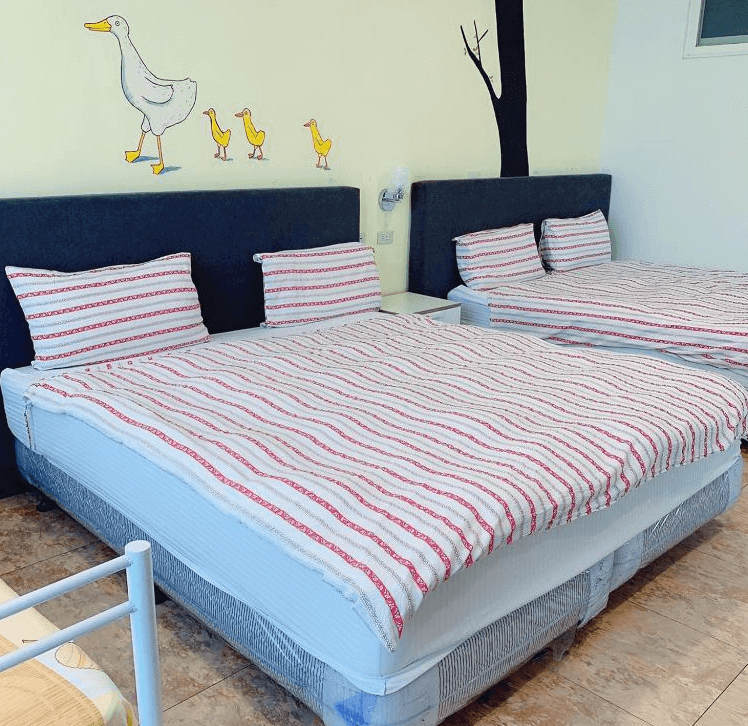 【西螺住宿】西螺後街童畫民宿雙床房，牆上彩繪親子鴨圖樣，床舖鋪上紅白條紋被單，營造溫馨童趣氛圍。