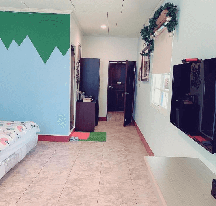 【西螺住宿】西螺後街童畫民宿客房一隅，牆面以藍綠山型圖案裝飾，配有液晶電視、基本茶水備品與乾淨明亮的通道空間。