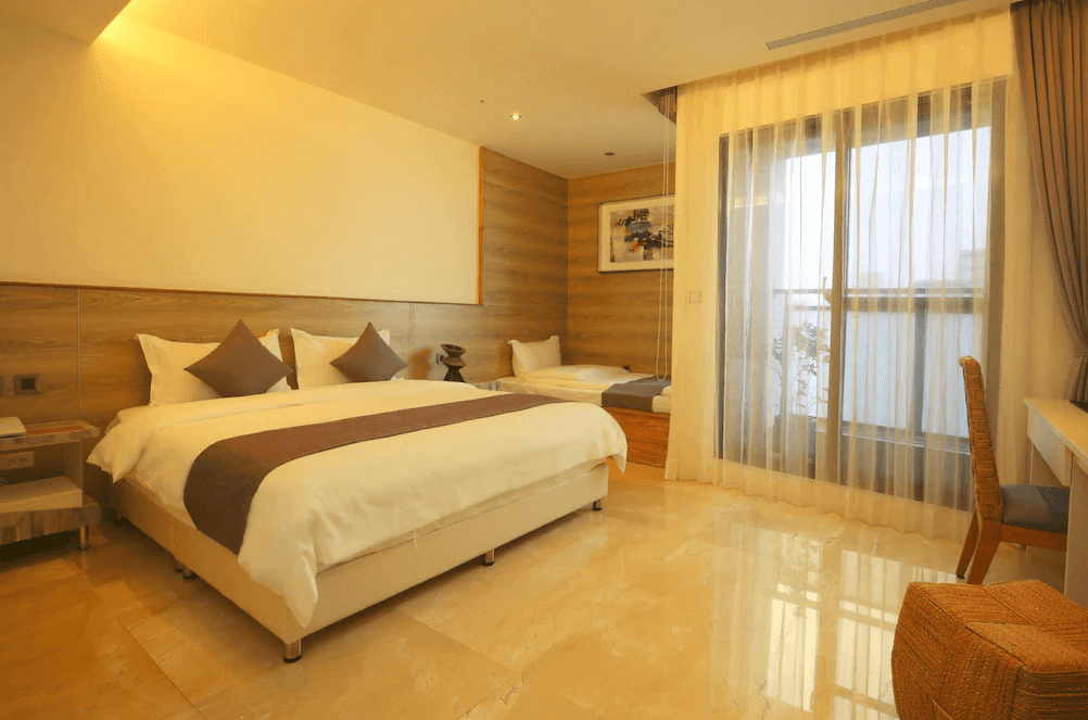 【新竹東區住宿】達龍商旅溫馨家庭房，設有一張雙人床與一張單人床，搭配大片落地窗與木紋牆面，空間寬敞明亮、自然採光充足。