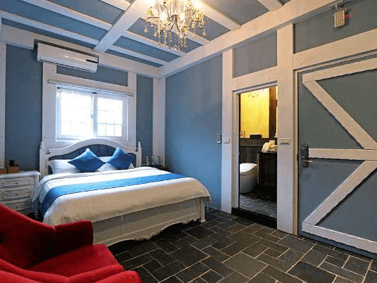 【花蓮寵物友善飯店】都鐸王朝藍白配色主題房，設有典雅吊燈與鄉村風木門，房內備有雙人床與紅色休憩椅，空間溫馨且風格獨具。