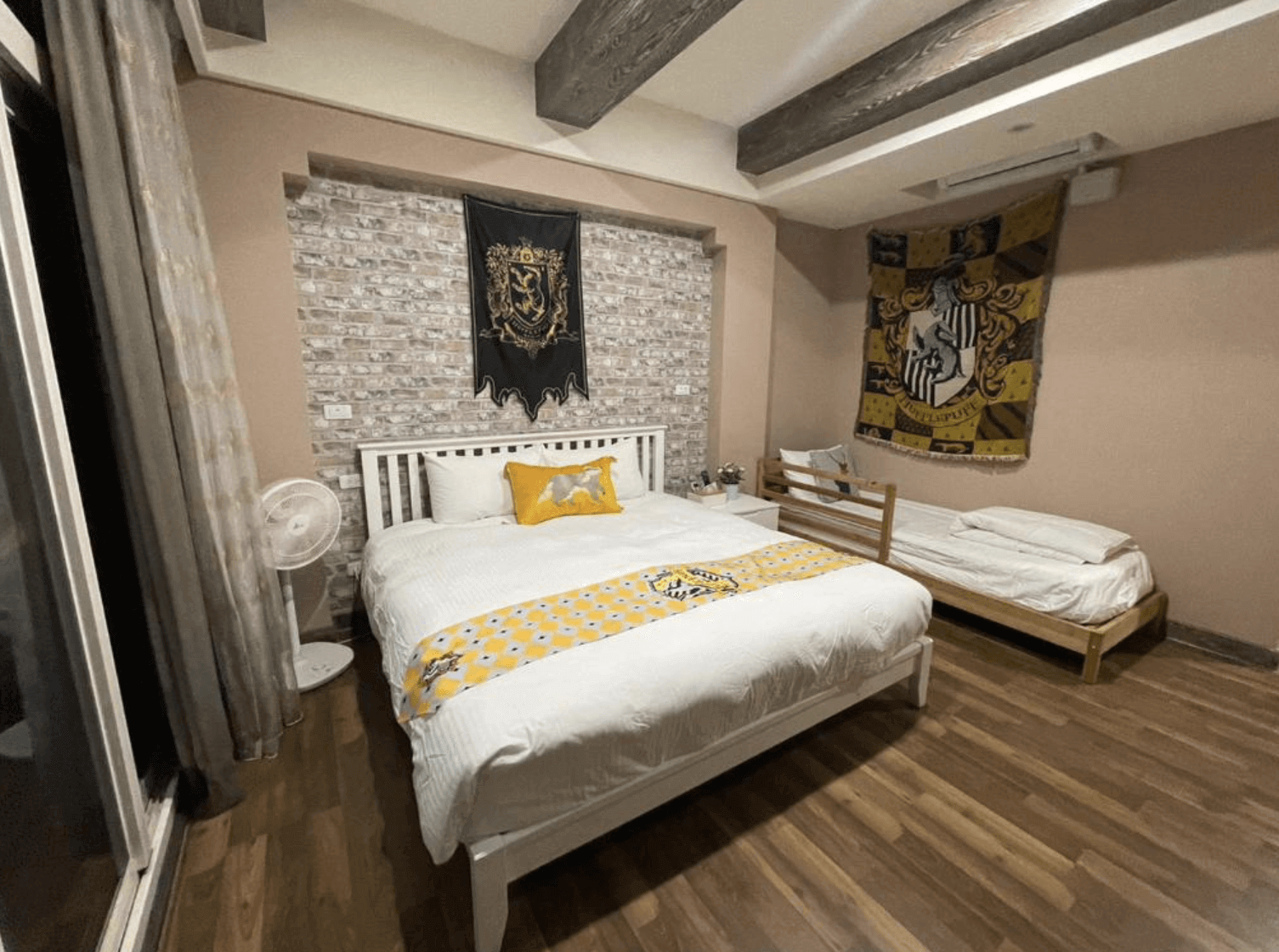 【清水住宿】鹿莫思 LUMOS 哈利波特赫夫帕夫主題房，磚牆搭配木質地板，設有雙人床與單人床，裝飾有學院色系床旗與掛布。