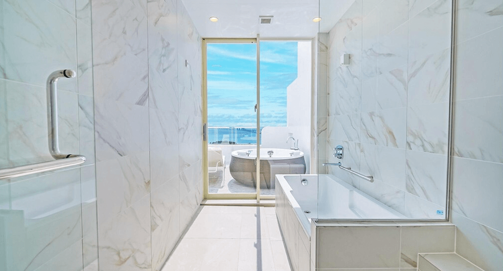 【宮古島住宿】Santorini酒店＆別墅內的高級大理石浴室，設有浴缸與通往戶外露天浴缸的玻璃門，外可眺望湛藍大海。