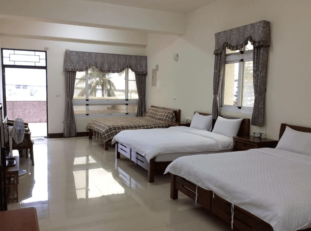 【金崙住宿】"太麻里住宿"三和民宿家庭房，設有兩張雙人床與一張單人床，室內寬敞明亮，窗外可見棕櫚樹與自然景色。
