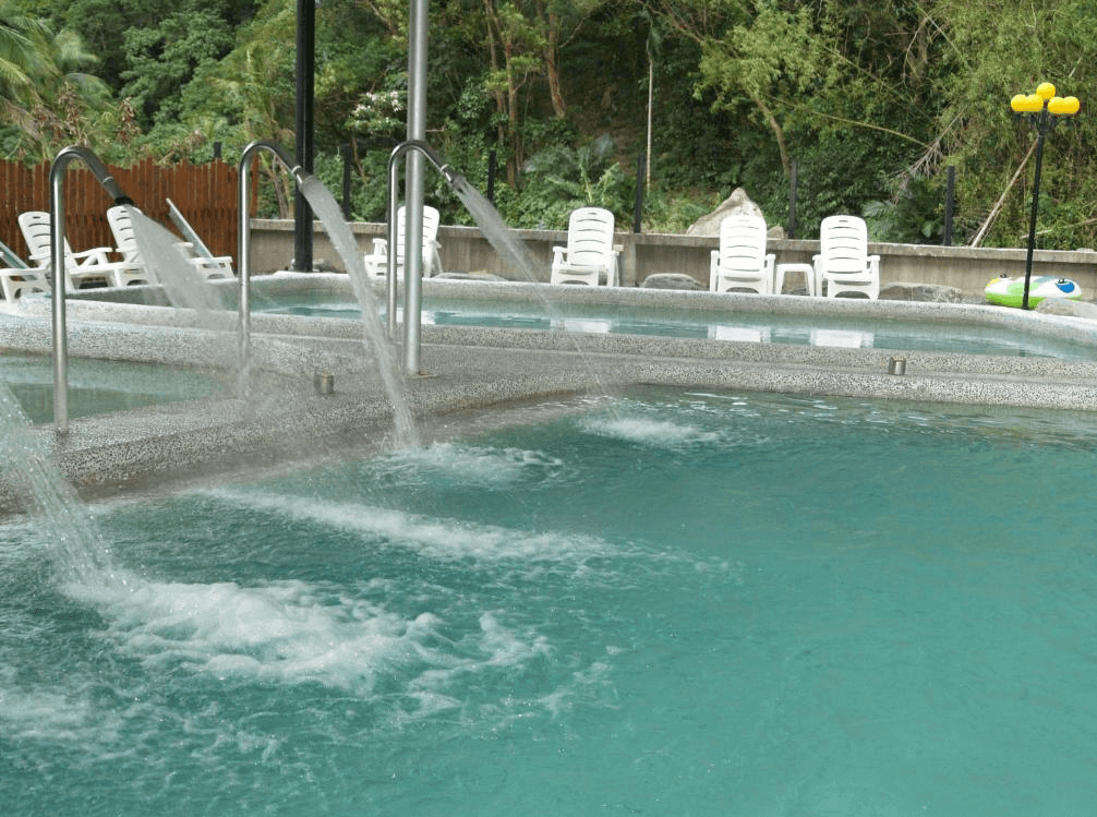 【金崙住宿】"太麻里住宿"丹堤溫泉會館露天大眾溫泉池，多股水柱按摩設施，池畔擺放白色休閒躺椅，可邊泡湯邊欣賞山林景色。