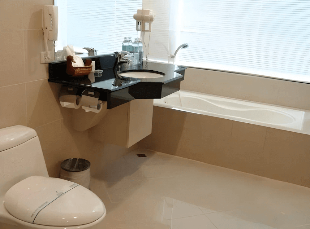 【板橋住宿】冠君大飯店 浴室空間，設有浴缸、洗手台與馬桶，整體採用米色系設計，乾淨明亮。