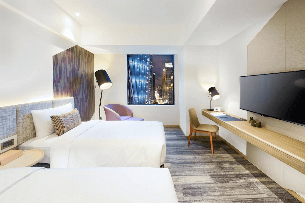 【板橋住宿】台北趣淘漫旅 雙床房，現代簡約設計，窗外可欣賞市區夜景，房內配有舒適書桌與大螢幕電視，適合旅遊或商務住宿。