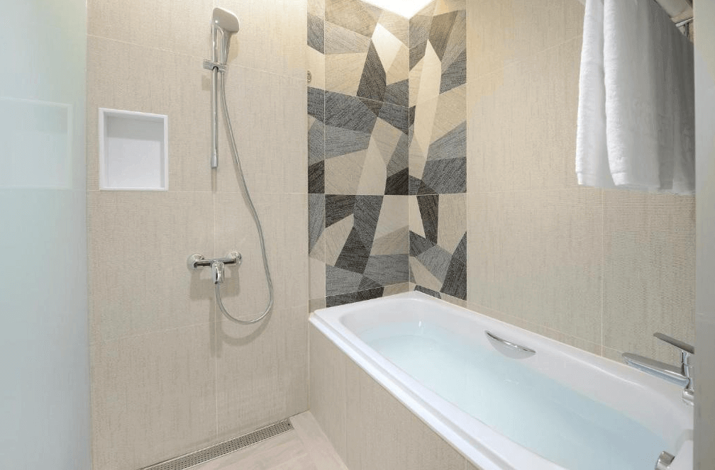 【板橋住宿】台北趣淘漫旅 浴室設有浴缸與淋浴，牆面以幾何拼接設計打造現代感，空間乾淨明亮。