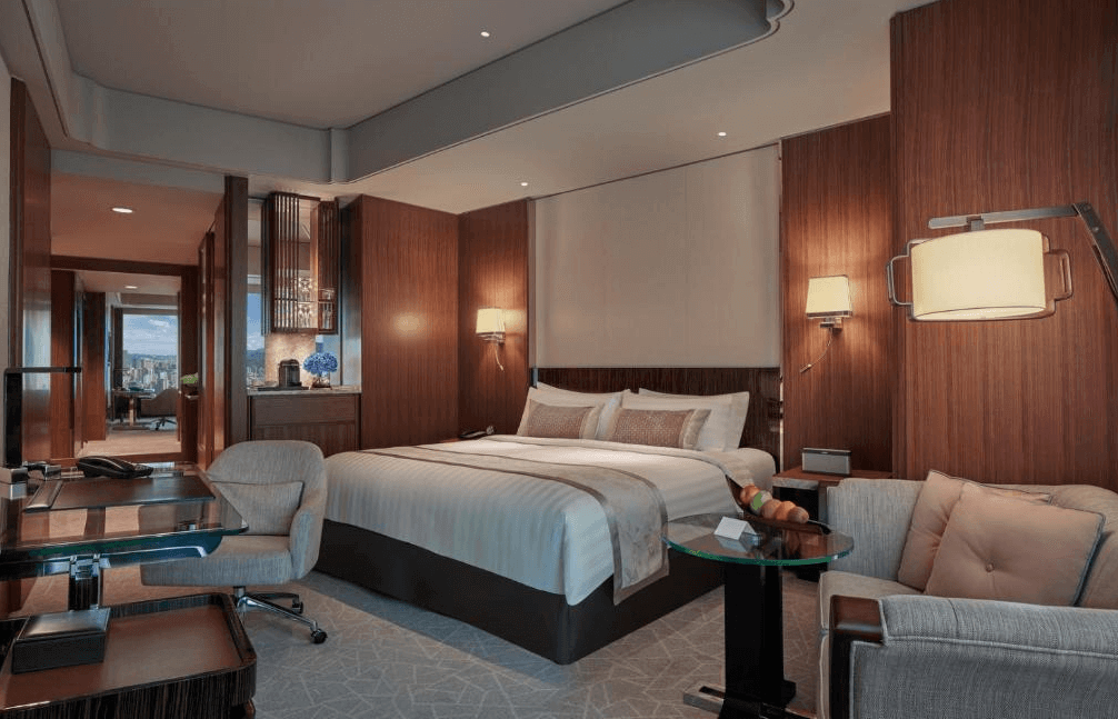 【大安住宿】台北遠東香格里拉豪華客房 —— 現代木質設計，雙人大床搭配米色與咖啡色調，附設書桌與沙發座椅，氛圍典雅舒適。