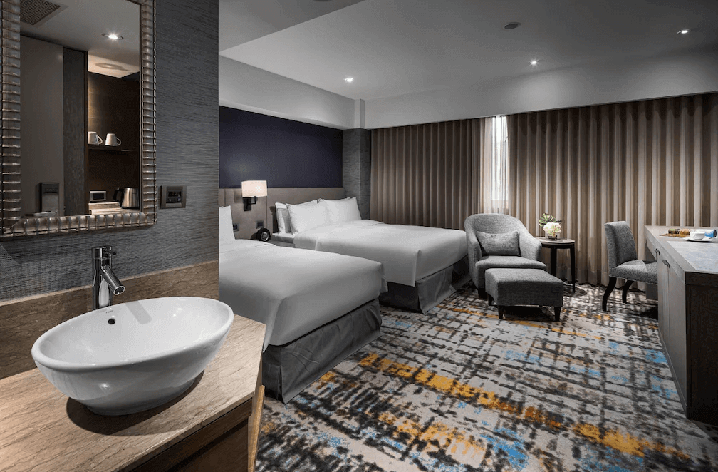 【大安住宿】台北馥敦復南館雙床客房 —— 現代典雅設計，兩張舒適雙人床搭配灰色調沙發與工作桌，房內採光柔和，空間寬敞。