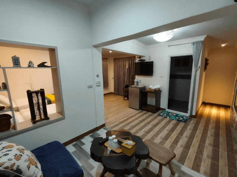 【太麻里住宿】吉廬夫敢藝文民宿室內起居空間，設有沙發、小茶几與木椅，牆上擺放手工藝品，並附有冰箱、電視與茶水區。