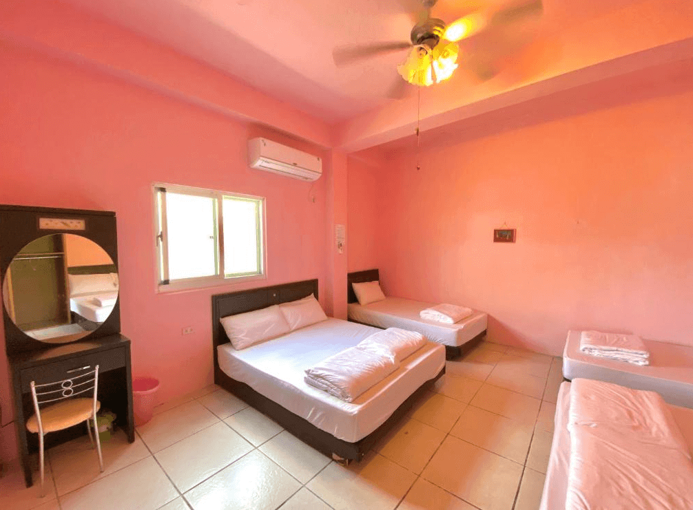 【蘭嶼住宿】嘟嘟悟的家家庭房：粉色牆面溫馨設計，擺放一張雙人床與兩張單人床，另設有梳妝台與圓鏡，房間採光良好。