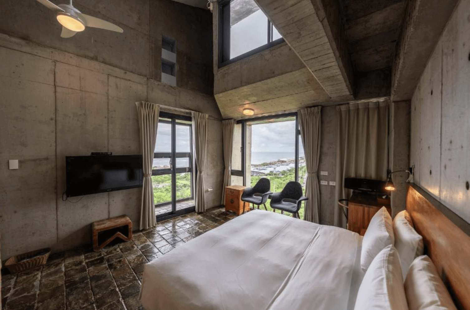 【恆春住宿】墾丁光現旅宿樓中樓景觀房型，挑高天花與落地窗引入自然光，享有絕佳海景視野，搭配簡約工業設計與柔和米白窗簾，展現極簡舒適氛圍。