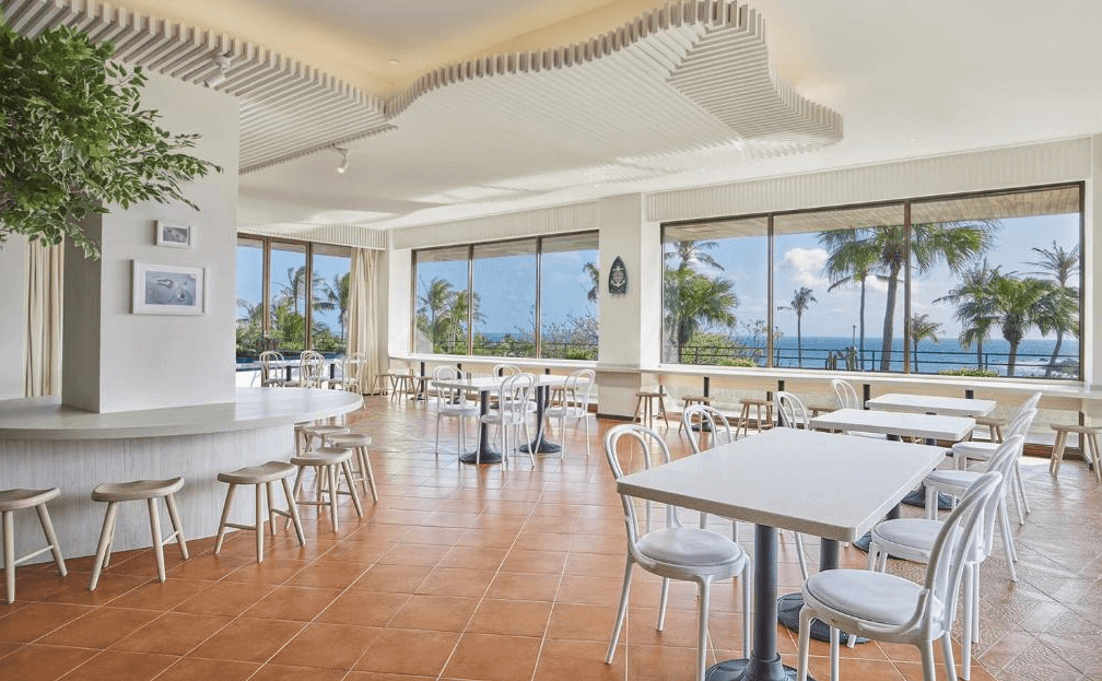 【墾丁寵物友善住宿】墾丁凱撒大飯店餐廳 — 明亮寬敞的用餐區，大片落地窗可欣賞熱帶棕櫚樹與海景，搭配白色桌椅與橘色地磚，營造悠閒度假氛圍