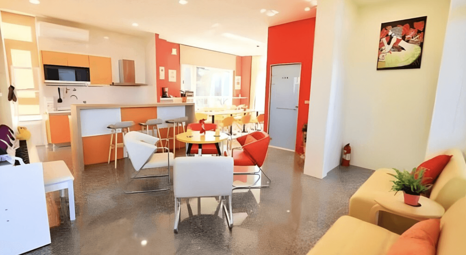 【恆春住宿】墾丁白沙灣玹玹映月民宿的公共交誼廳與餐廚區，空間寬敞明亮，配有多組座椅、吧台及廚房設施，整體色調活潑鮮明，適合親友聚會交流。