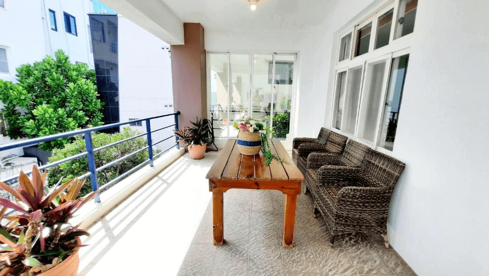 【墾丁寵物友善住宿】墾丁青山旅店陽台休憩區 — 寬敞陽台配有木質桌椅與藤編沙發，四周擺放盆栽，適合放鬆賞景。