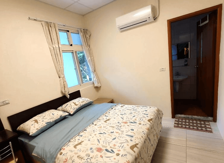 【太麻里住宿】太麻里左奶奶的家雙人房，簡約設計搭配木質床架與花卉圖案床單，窗外透進自然光，附設獨立衛浴。