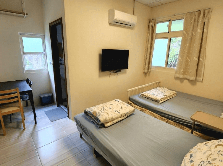 【太麻里住宿】太麻里左奶奶的家家庭房，兩張單人床搭配簡單書桌與電視，米色牆面營造溫馨氛圍，適合親子入住。