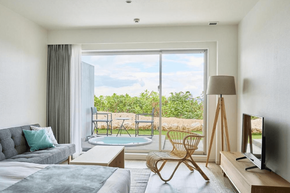 【宮古島住宿】宮古島水印飯店的客房設有舒適沙發與電視，延伸至戶外露天泡湯池與座椅區，打造靜謐自在的私人療癒空間。
