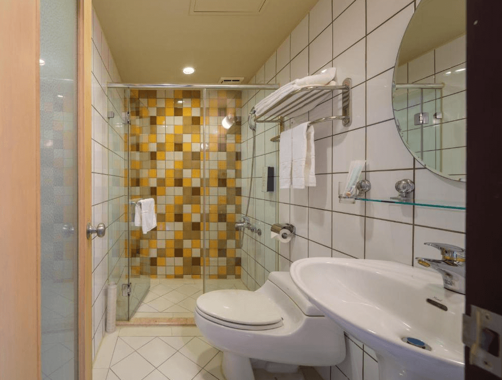 【板橋住宿】富逸旅趣-板橋府中館 浴室設施 – 現代化浴室，內有淋浴間、洗手台與馬桶，黃色與白色相間的磁磚牆面設計，乾淨明亮。