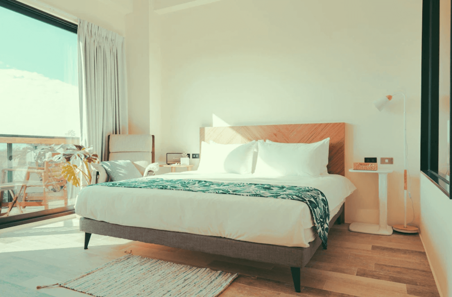 【恆春住宿】《墾丁白砂15 Villa民宿》房間內景，配有舒適雙人床、木質地板、大面採光窗與陽台座椅，自然光灑落整間房間，營造溫暖靜謐的氛圍。