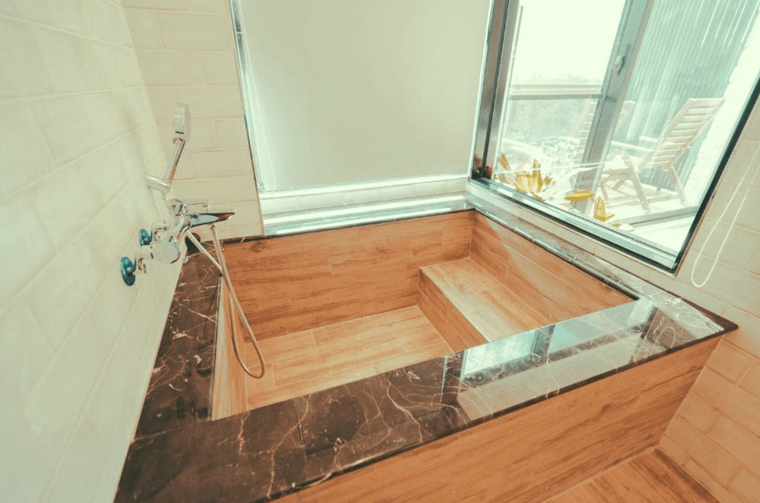 【恆春住宿】《墾丁白砂15 Villa民宿》景觀浴池，採用木質調與黑色大理石檯面設計，靠窗位置可眺望戶外自然風景，泡澡同時享受陽光與森林氣息。