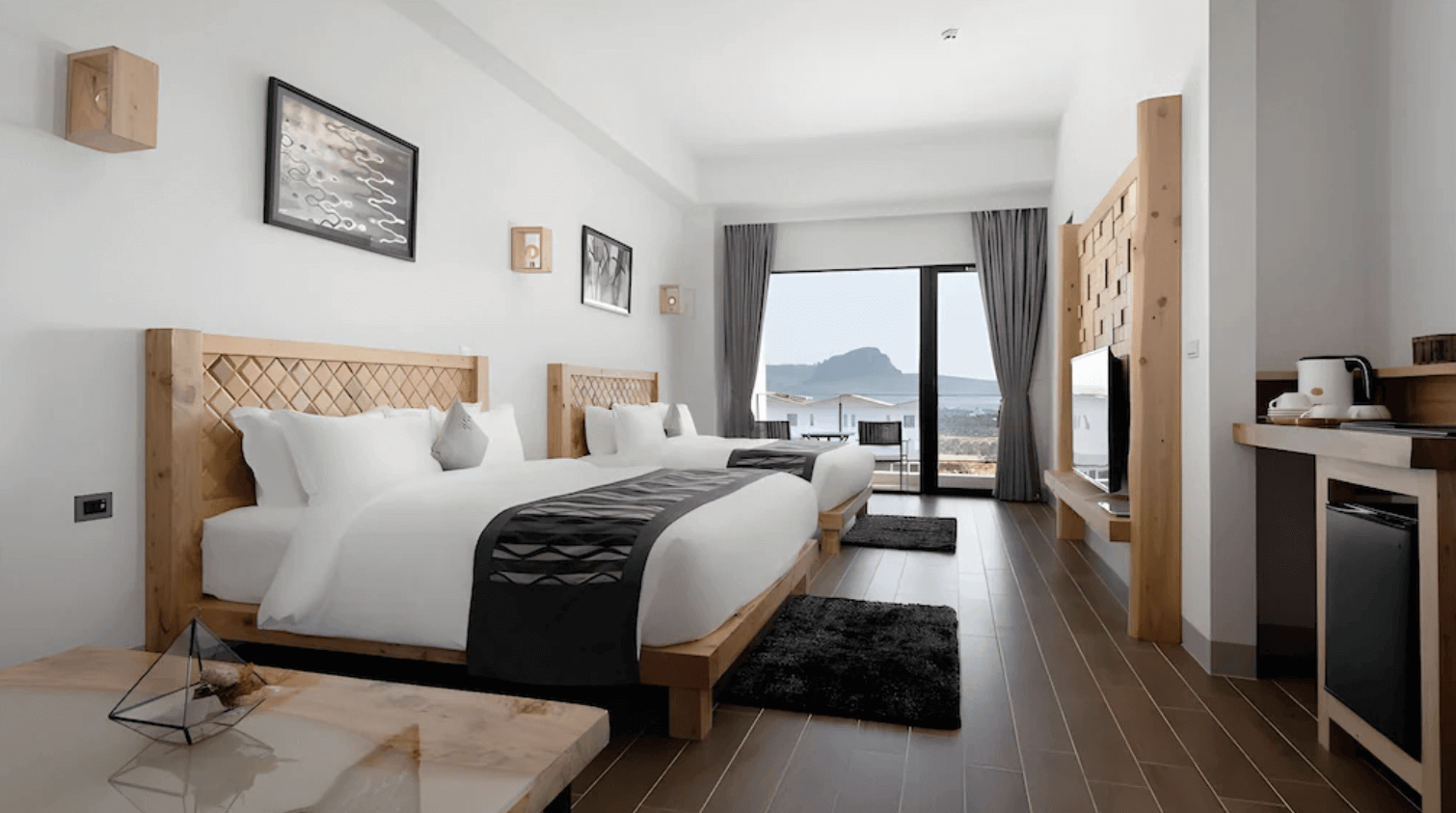 【恆春住宿】嵐翎白砂渡假莊園雙床房型，室內採用大量原木元素，擁有大片落地窗與遠方山海景色，空間明亮舒適，附有小型茶水吧與電視。