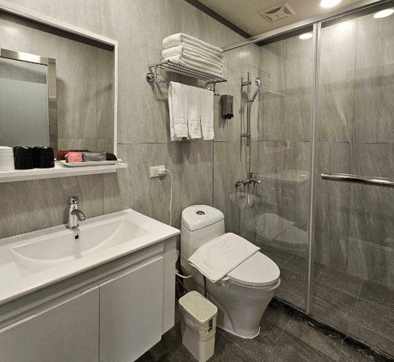 【板橋住宿】旅居文旅板橋車站館浴室：現代化浴室設計，乾濕分離淋浴間，白色洗手台搭配大鏡子，備有盥洗用品與毛巾，整體乾淨明亮。