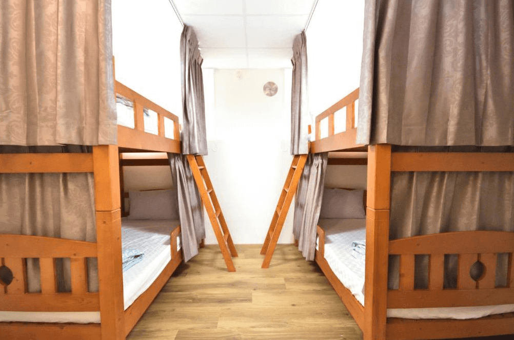 【金崙住宿】"太麻里住宿"東金民宿多人宿舍房，設有上下舖木質床架，每張床位附有窗簾保障隱私，簡潔明亮的住宿空間。