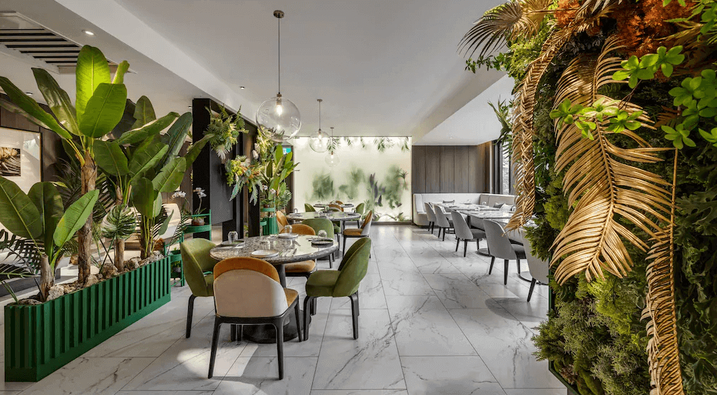 【板橋住宿】板橋凱撒大飯店 餐廳環境，室內綠植點綴、圓桌與舒適座椅，營造自然清新氛圍。