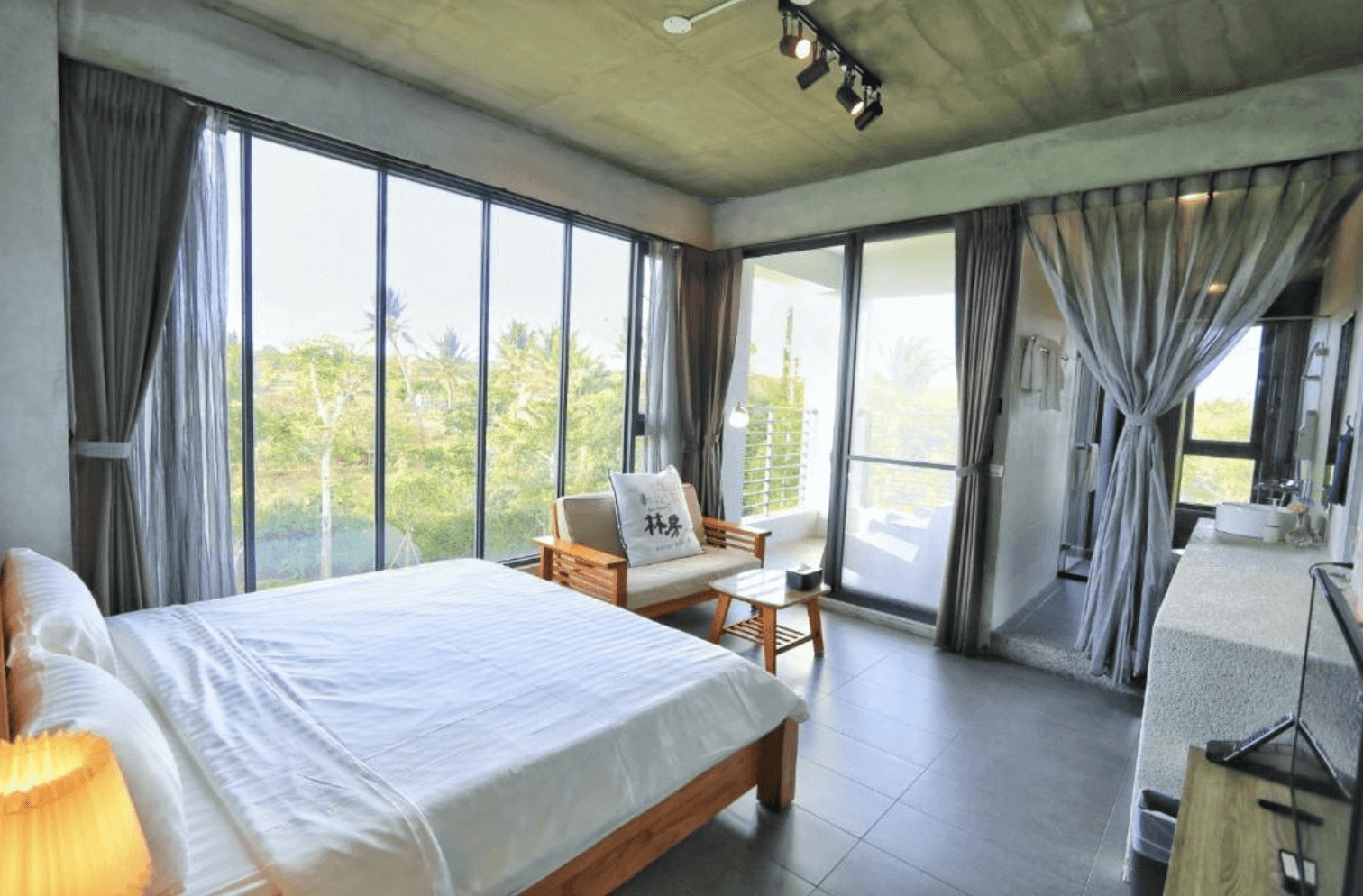 【恆春住宿】林房 Lin’s Forest 一大床房型，落地窗引入滿滿綠意與陽光，空間設計簡約工業風，附有原木沙發與陽台，感受大自然環抱的清新住宿體驗。