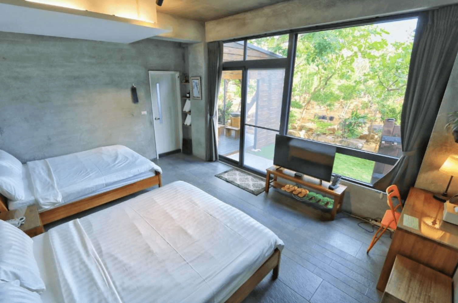 【恆春住宿】林房 Lin’s Forest 雙床房型，大片落地窗面對自然庭園，房內設有木質書桌與電視，空間舒適且富有生活感，適合親子或朋友同行入住。